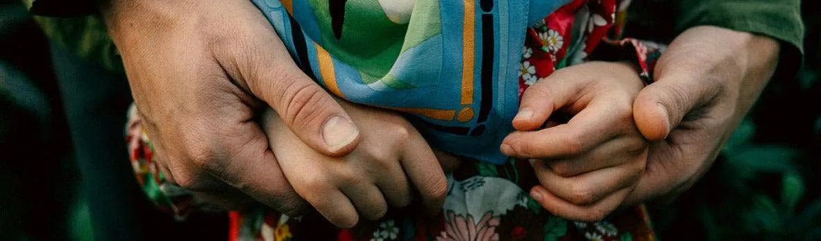 Grown hands holding child hands.