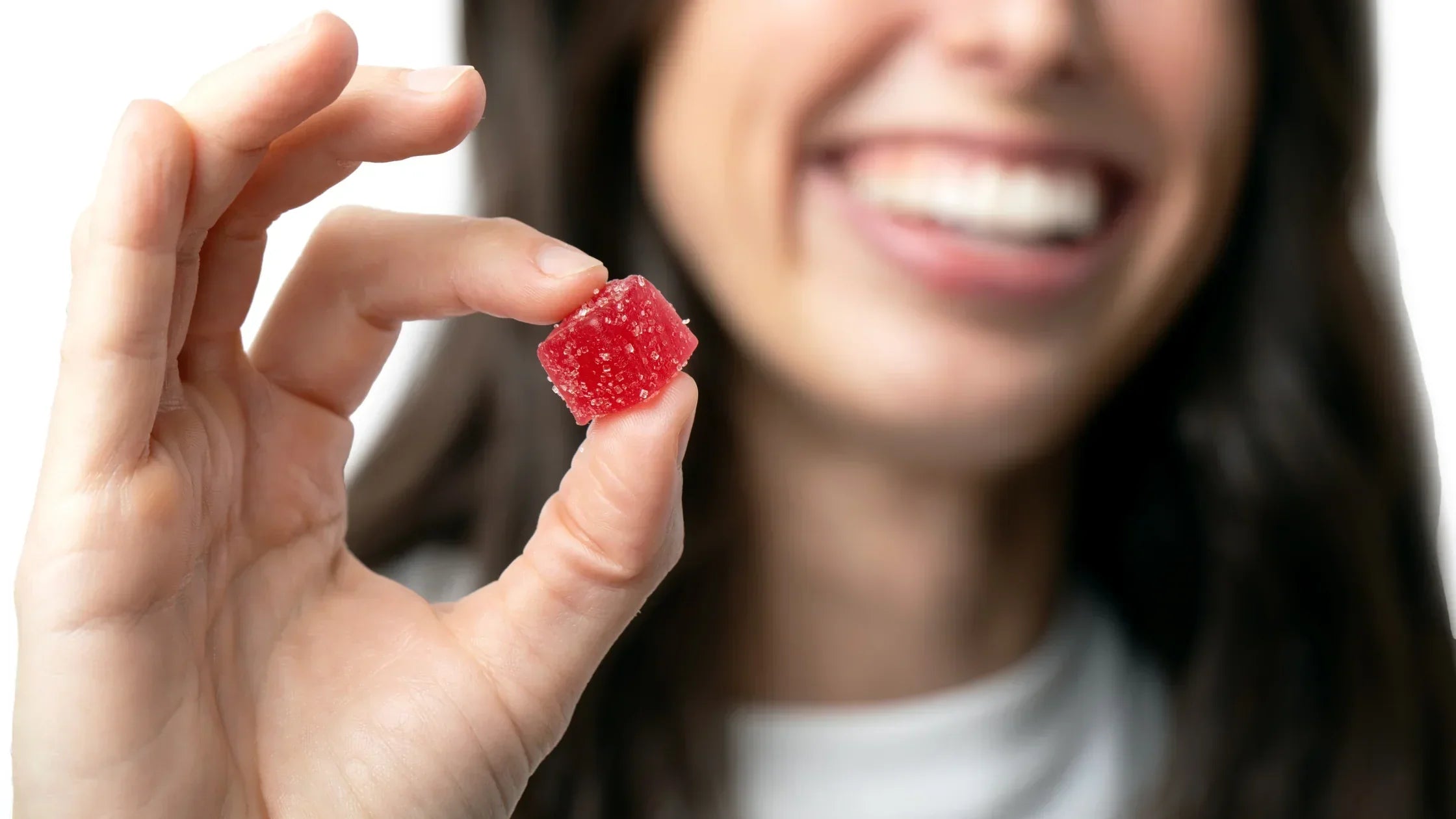 Closeup of a woman holding out a Charlotte's Web Brightside gummy.