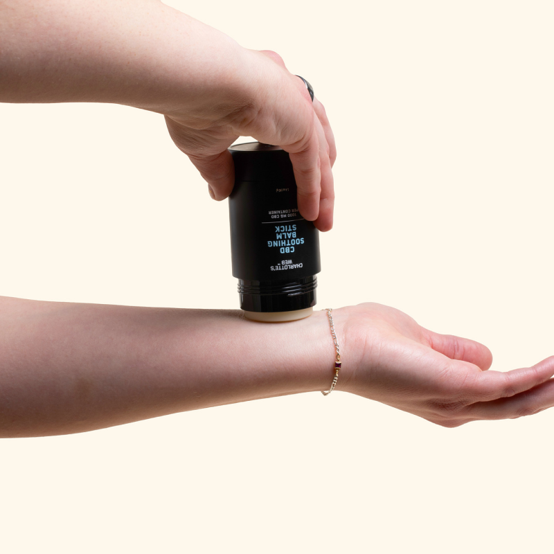 Person rubbing the soothing balm stick on arm