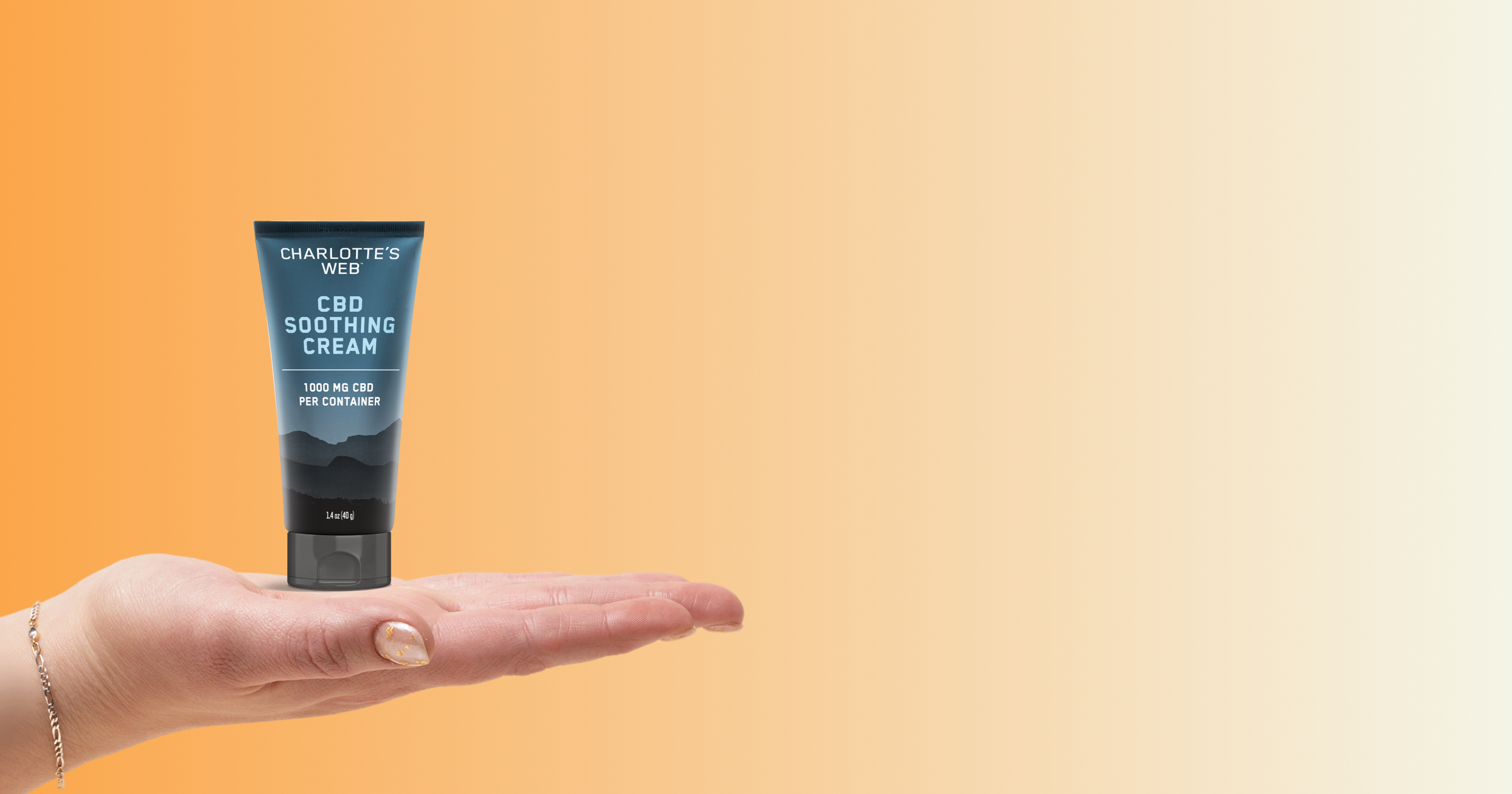Palm holding a tube of CBD Soothing Cream on an orange background