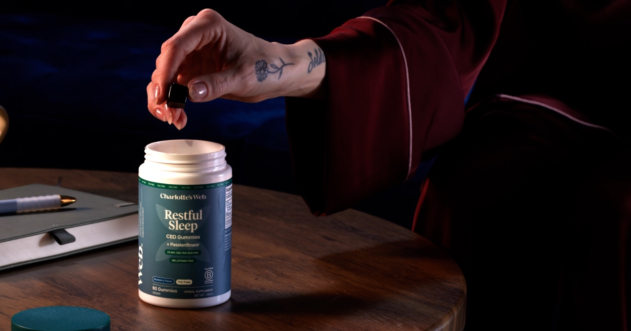 Person opening a bottle labeled 'Restful Sleep' on a wooden surface.