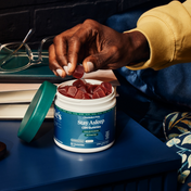 Product Image for Person holding a supplement container labeled 'Stay Asleep' with gummy supplements on a desk.