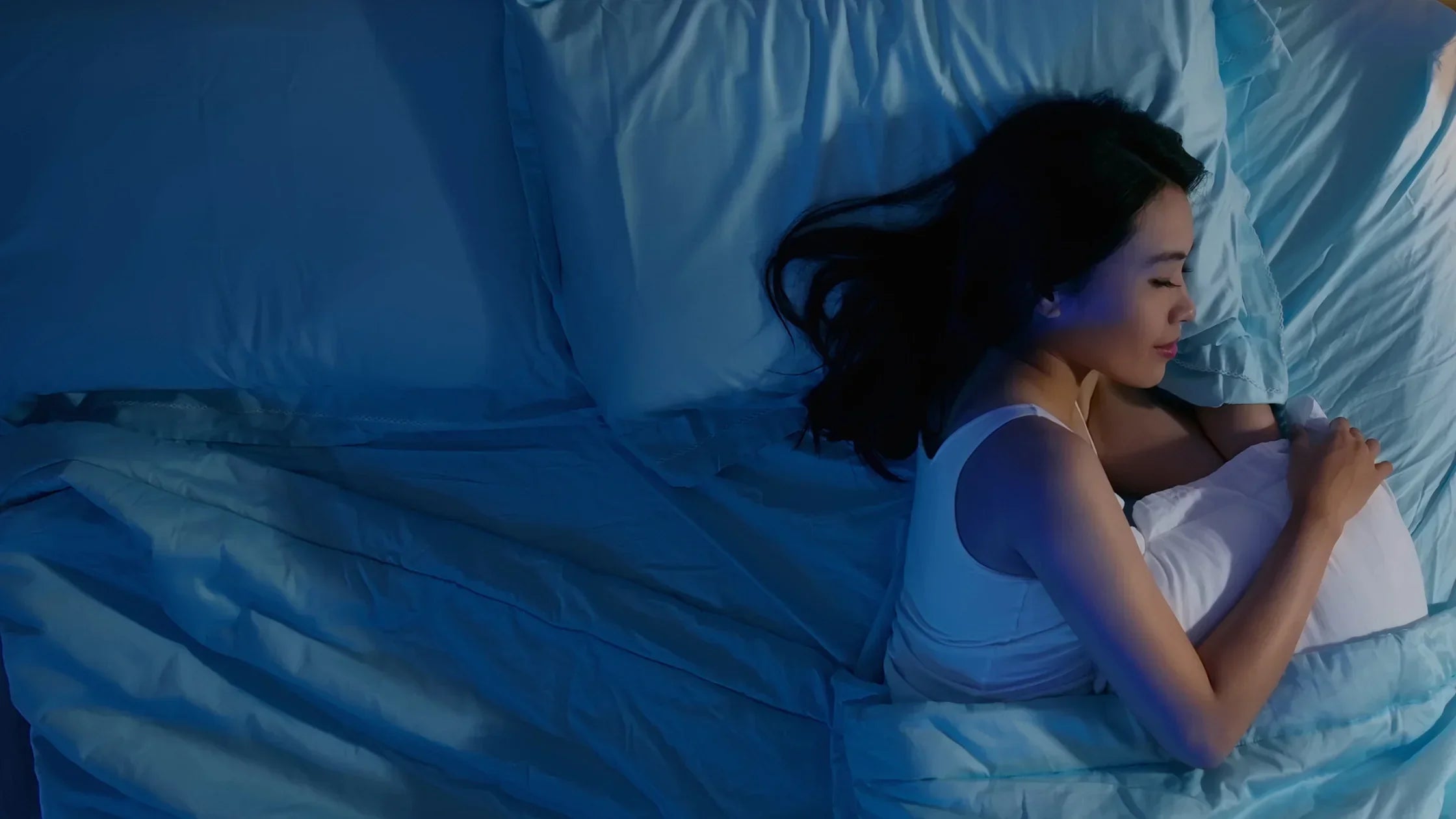 Woman sleeping through the night, looking cozy and well-rested as a result of using a CBN supplement.