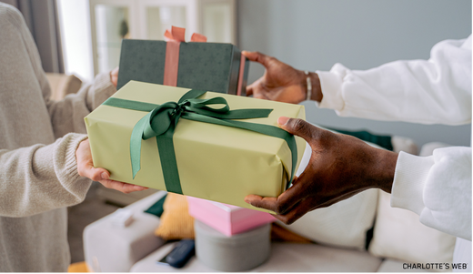 A person handing another person a beautifully wrapped gift to celebrate. 