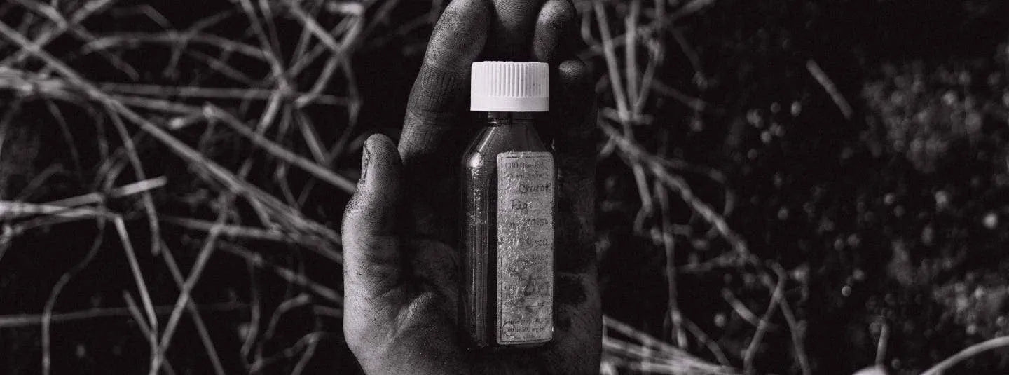 Black and white image of a hand cradling a bottle.