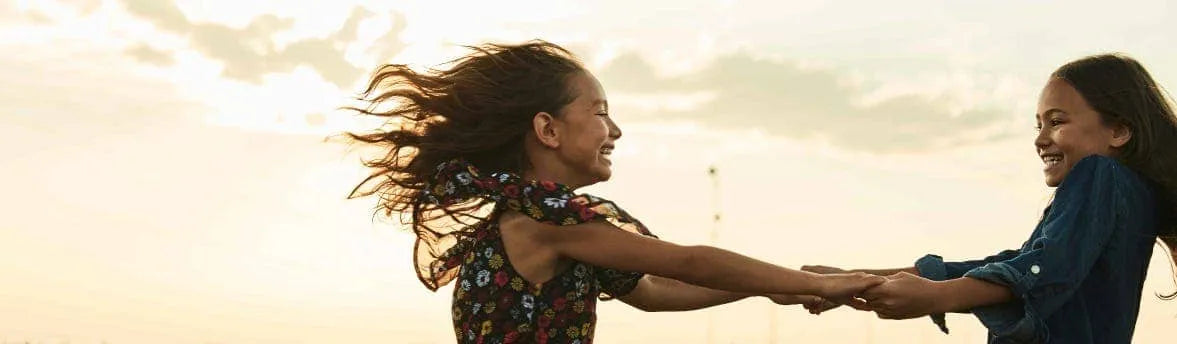 Two young girls playing a game with their hair blowing in the wind.
