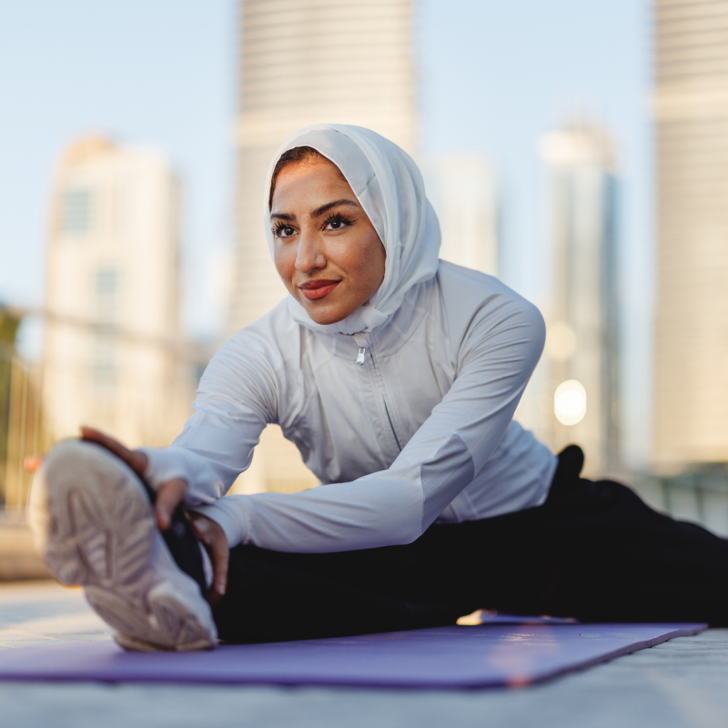 Woman in grey zip up stretching outside on rooftop