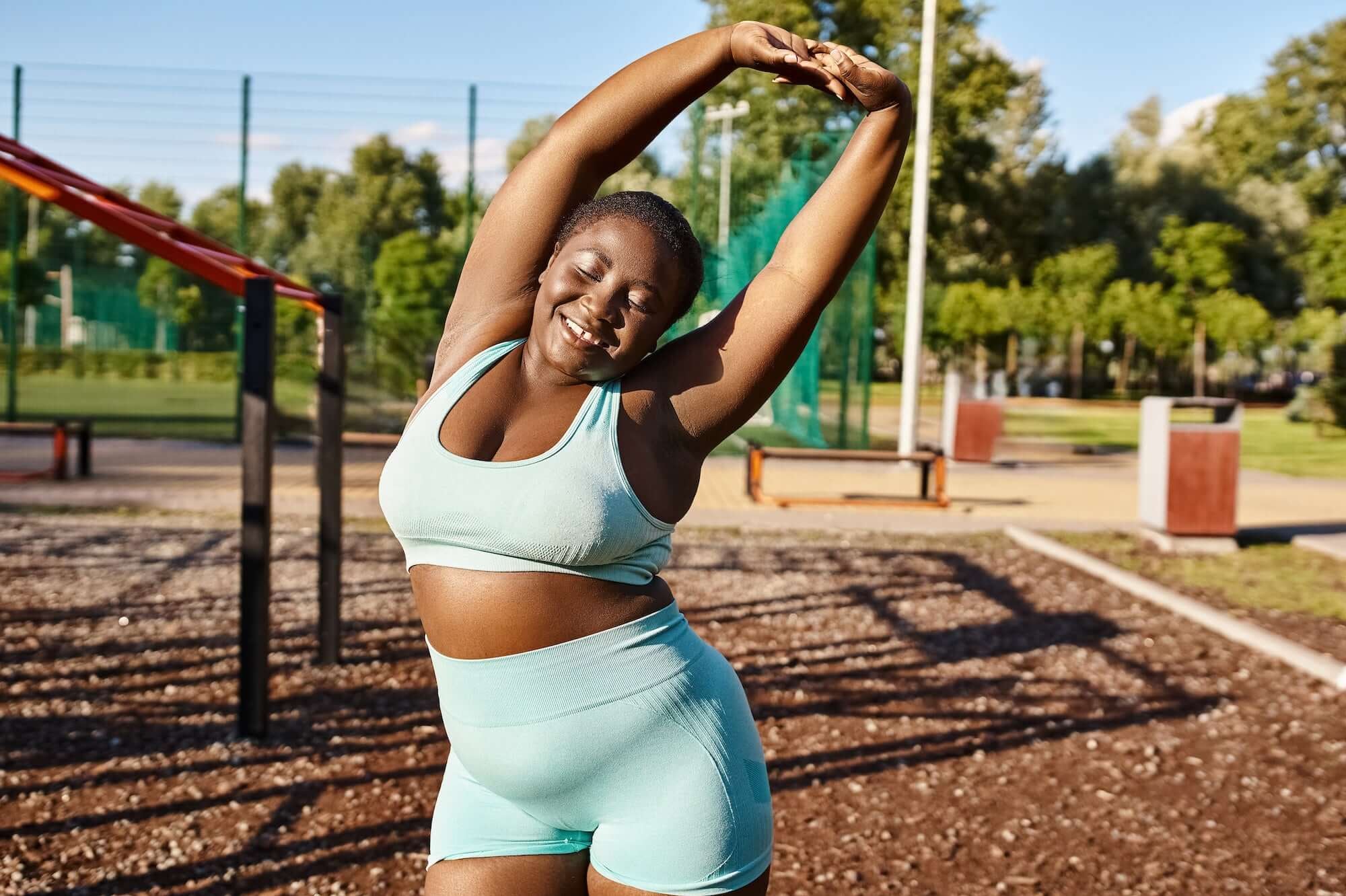 Woman in a blue active wear set stretching in a park setting
