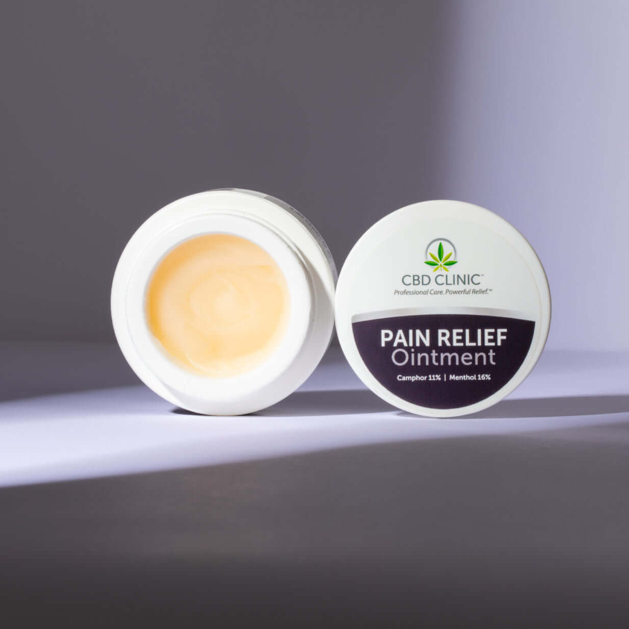 CBD Clinic Pain Relief Ointment jar with open lid on a gray background