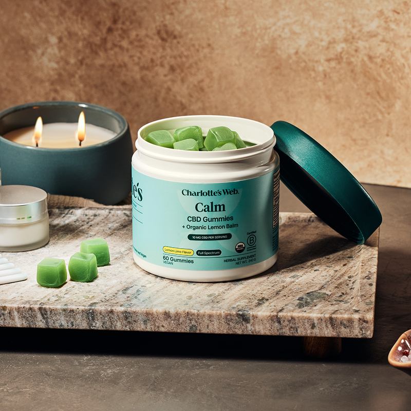 Charlotte's Web calm gummies jar on stone plate with lit candle