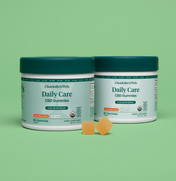 Product Image for Two jars of Charlotte&#39;s Web Daily Care CBD Gummies on a green background