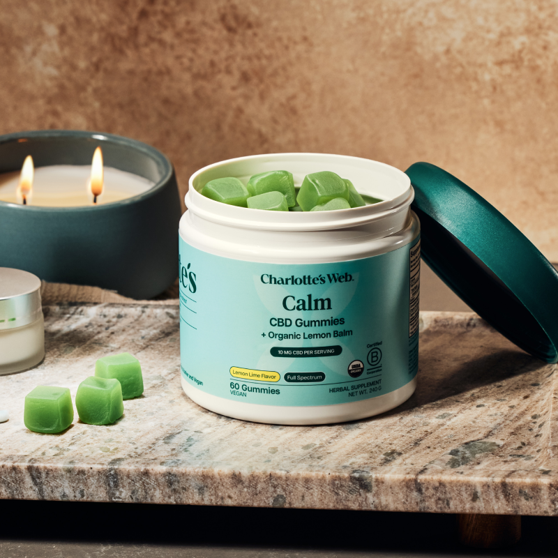 Gummies product on a wooden tray with green leaves and a neutral background