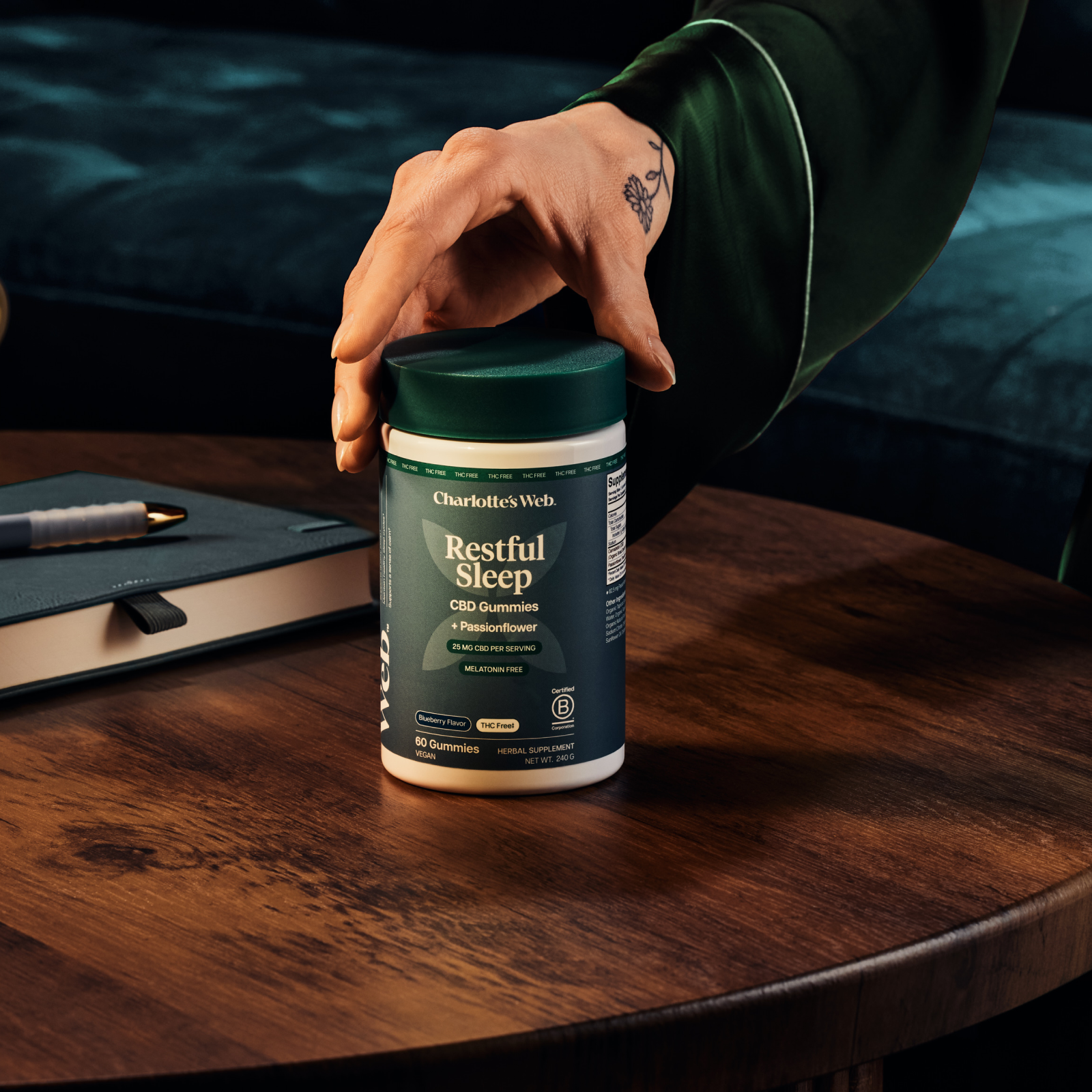 Product Image for Hand holding a container of &#39;Restful Sleep&#39; supplement on a wooden table with a blurred background
