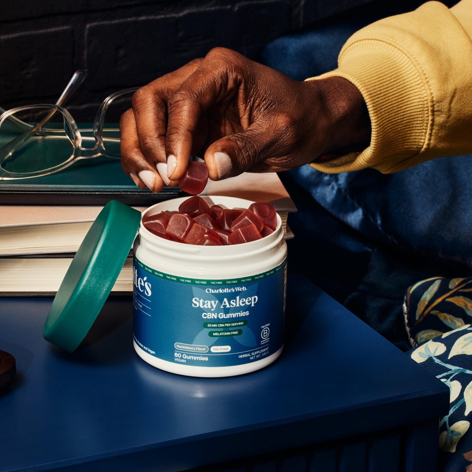 Product Image for Person holding a supplement container labeled &#39;Stay Asleep&#39; with gummy supplements on a desk.
