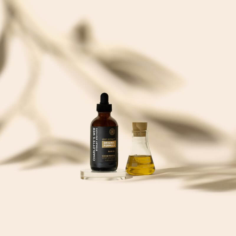 Two bottles of Charlotte's Web products on a neutral background