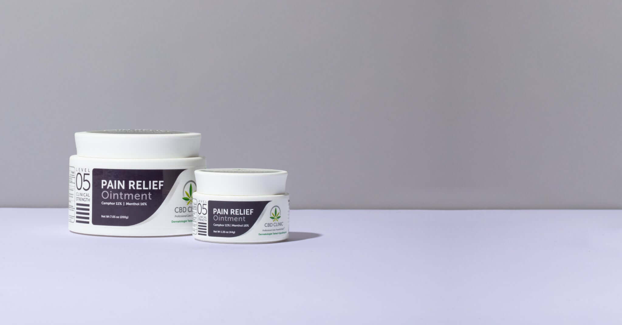 Two jars of pain relief ointment on a light gray background